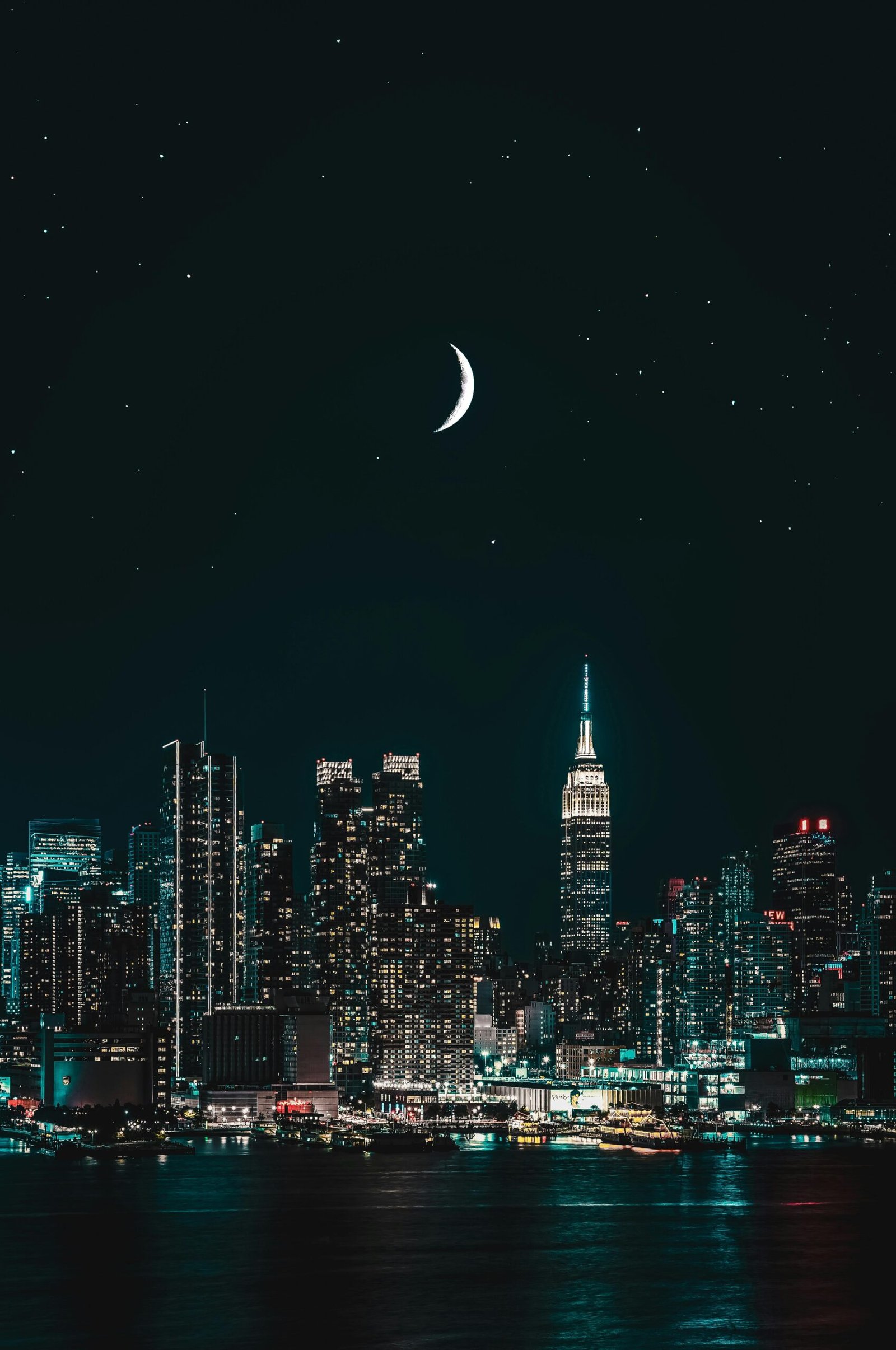Stunning night view of New York City skyline with a crescent moon and stars illuminating the scene.