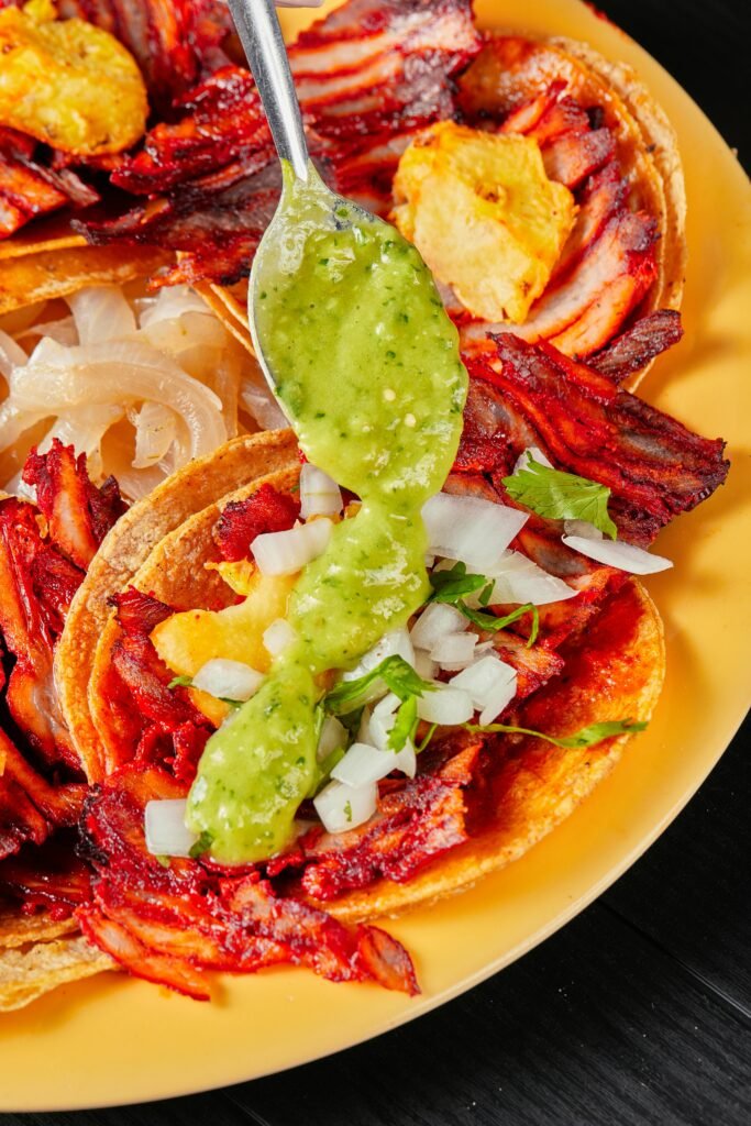 Close-up of tasty tacos topped with salsa verde, perfect for Mexican food lovers.